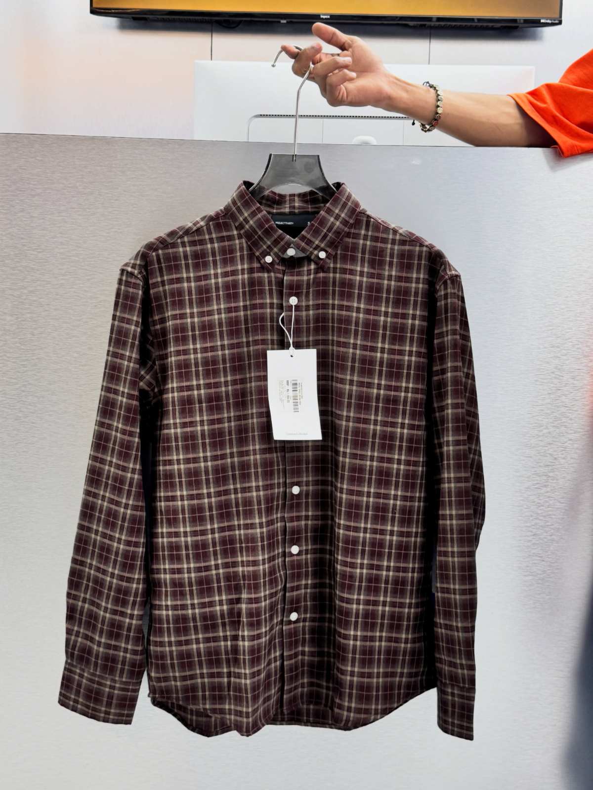 Brown tartan check flannel shirt on a hanger