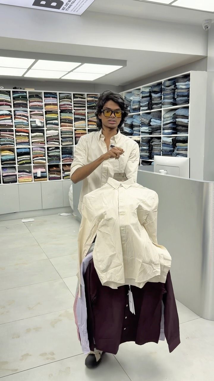 Model holding cream and maroon oxford shirts inside the Borntown store